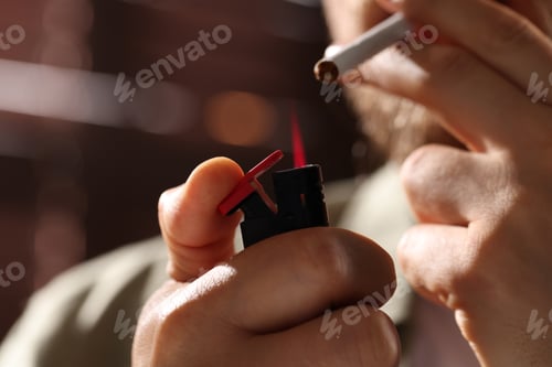Preview: Man lightning cigarette against blurred brown background, closeup