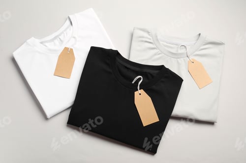 Preview: Blank folded t-shirts with tags on light grey background, top view. Mockup for design