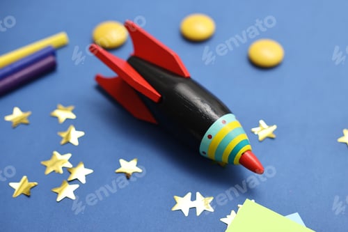 Preview: Toy rocket and art materials on blue table, closeup