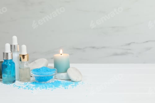 Preview: Different aromatherapy products and burning candle on white wooden table, space for text