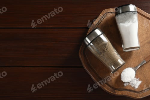 Preview: Salt and pepper shakers on wooden table, top view. Space for text