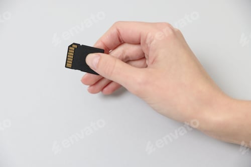 Preview: Woman with SD card on light background, closeup
