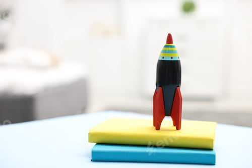 Preview: Toy rocket and books on light table indoors, closeup. Space for text