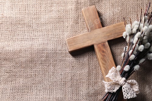 Preview: Cross and willow branches on beige cloth, flat lay. Space for text