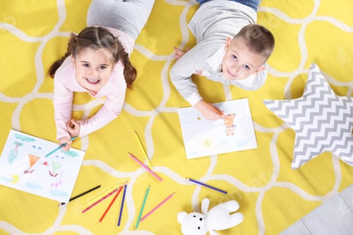 Preview: Children drawing with pencils on floor at home, top view