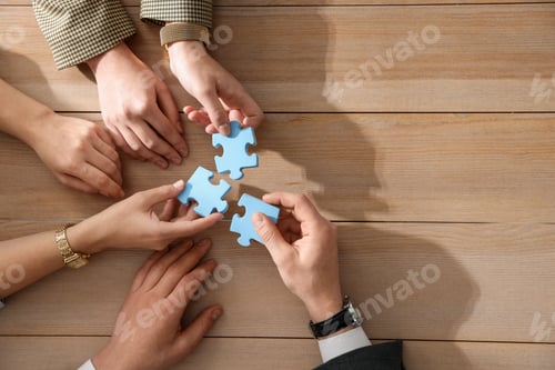 Preview: Team building. Group of businesspeople putting puzzle pieces together at wooden table, top view. Spa