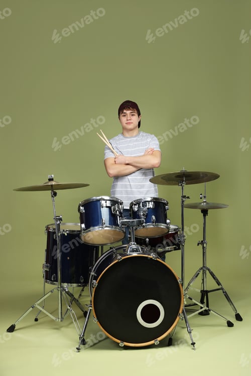 Preview: Teenage boy in baseball cap with drumsticks and drum kit on green background