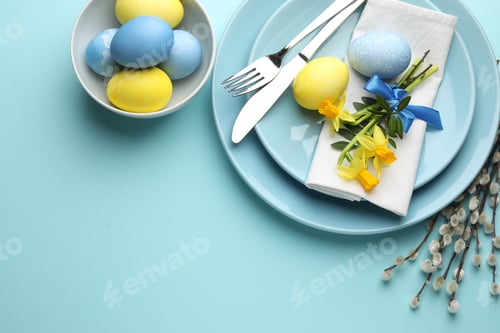 Preview: Easter celebration. Festive table setting with daffodil flowers, painted eggs and willow branches on