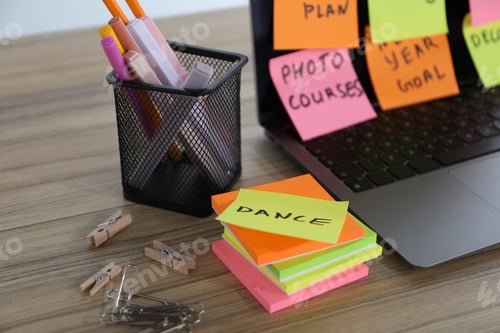 Preview: Laptop with colorful sticky notes and stationery on wooden table, closeup. Multitasking, deadline an