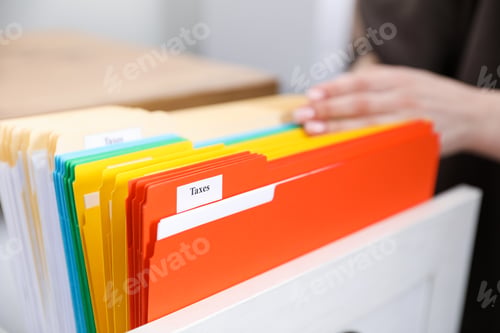 Preview: Tax. Woman looking through office folders in drawer of cabinet indoors, closeup