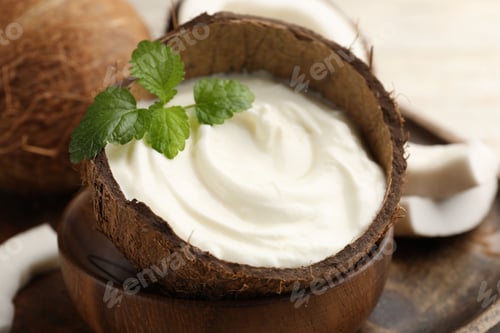 Preview: Tasty coconut yogurt with melissa leaves in shell on white table, closeup