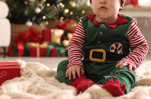 Preview: Little baby in elf costume on floor at home, closeup. Christmas season