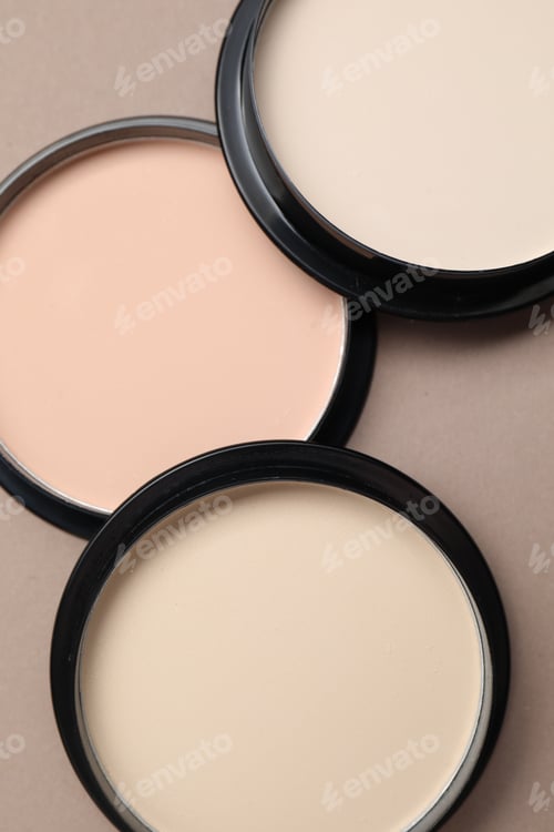 Preview: Face powder of different shades in containers on beige background, flat lay