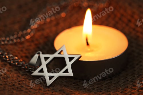 Preview: Holocaust Remembrance Day. Pendant in shape of Star of David and burning candle on burlap cloth, clo