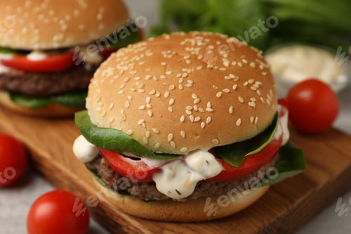 Preview: Delicious burger with meat patty on grey table, closeup