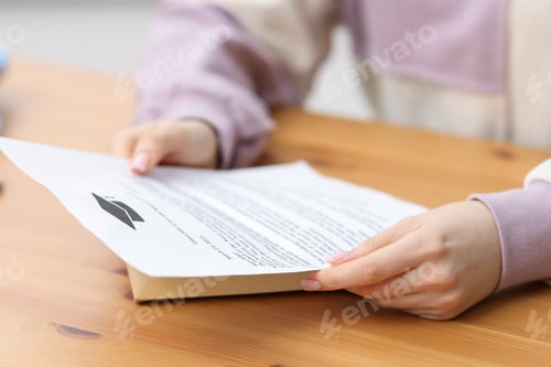 Preview: Woman with letter from university at wooden table indoors, closeup