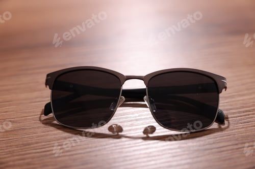 Preview: Stylish pair of sunglasses on wooden table, closeup