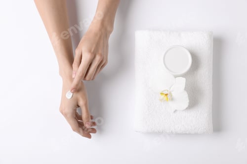 Preview: Woman with hand cream, towel and orchid on white background, top view