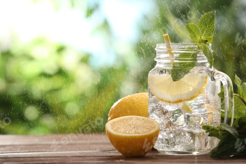 Preview: Lemon water in mason jar, mint and citrus fruits on wooden table against blurred background, closeup