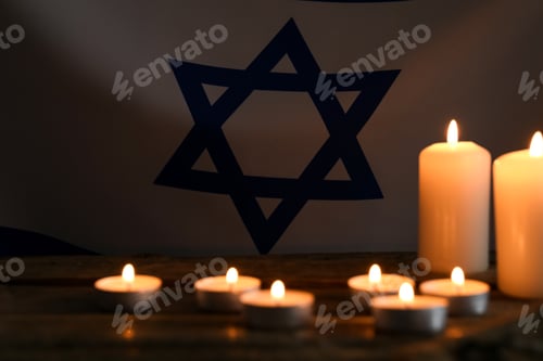 Preview: Holocaust Remembrance Day. Burning candles on table against flag of Israel, selective focus