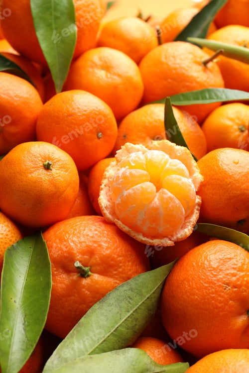 Preview: Many fresh ripe tangerines with green leaves as background, closeup