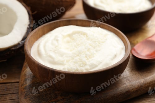 Preview: Tasty coconut yogurt with flakes and nuts on wooden table, closeup