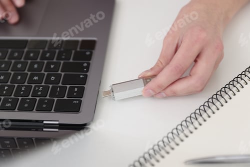 Preview: Woman connecting USB flash drive to laptop at desk, closeup