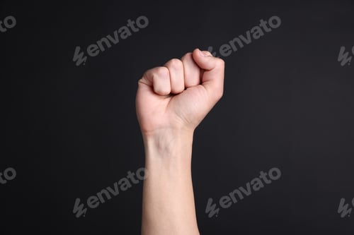 Preview: Man showing fist on black background, closeup