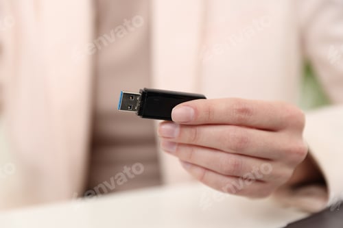 Preview: Woman with USB flash drive at desk, closeup
