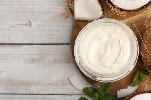 Preview: Delicious coconut yogurt in glass jar, mint leaves and fruits on white wooden table, flat lay. Space