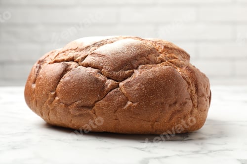 Preview: Loaf of fresh bread on white marble table, closeup