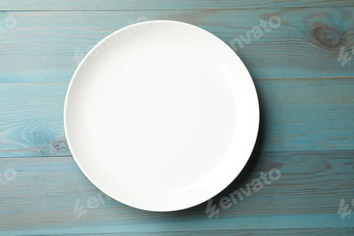 Preview: One empty plate on light blue wooden table, top view