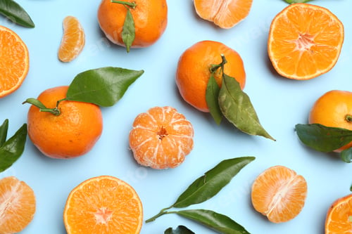 Preview: Fresh juicy tangerines and green leaves on light blue background, flat lay