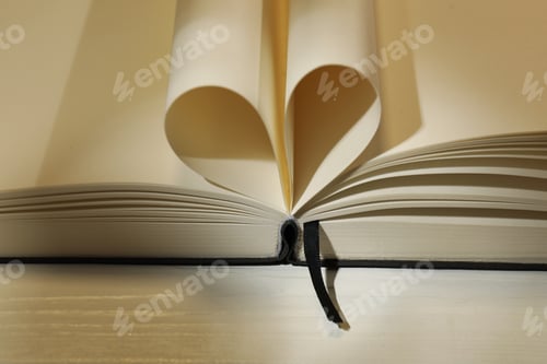 Preview: Love. Open book with pages folded in heart shape on table, closeup