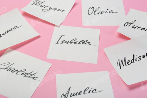 Preview: Paper stickers with different names on pink background, closeup. Choosing baby's name