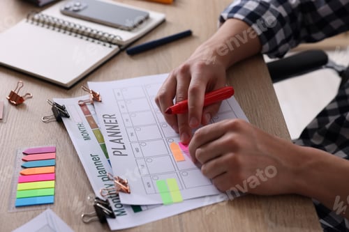 Preview: Man using planner at wooden table, closeup