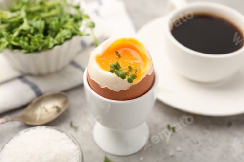 Preview: Tasty breakfast with soft boiled egg, microgreens, salt and coffee on grey table, closeup