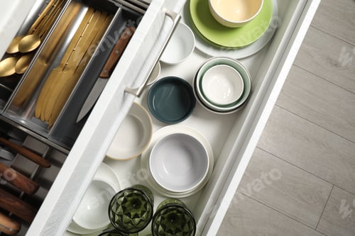 Preview: Ceramic dishware and cutlery in drawers indoors, top view
