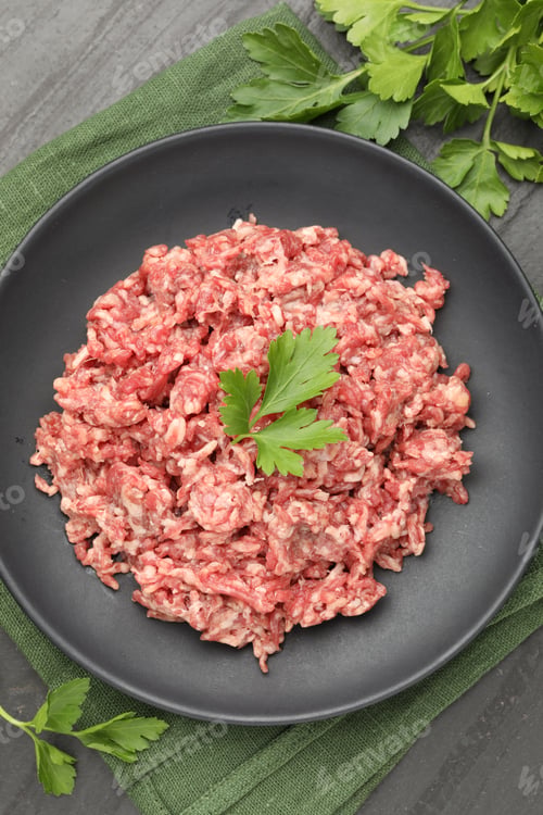 Preview: Raw minced beef and parsley on black table, flat lay