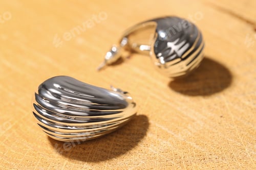 Preview: Beautiful silver earrings on wooden background, closeup