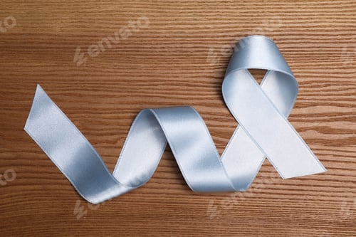 Preview: International Psoriasis Day. Ribbon as symbol of support on wooden table, top view