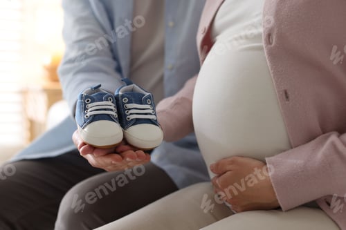 Preview: Couple with baby shoes at home, closeup