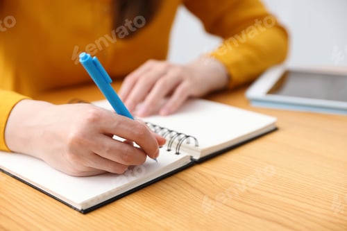 Preview: Woman working at wooden table with tablet indoors, closeup