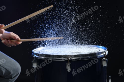 Preview: Man with drumsticks playing drum on black background, closeup