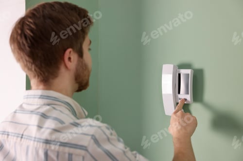 Preview: Man pressing button on intercom panel indoors
