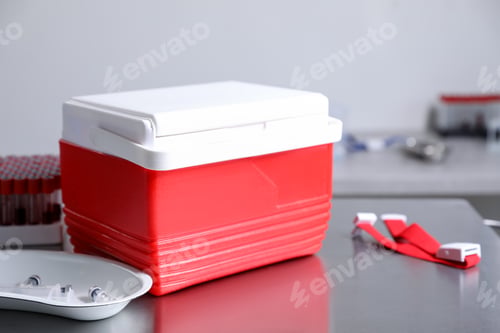 Preview: Cool box with ice cubes, test tubes of blood samples, syringe, vials and medical tourniquet on table