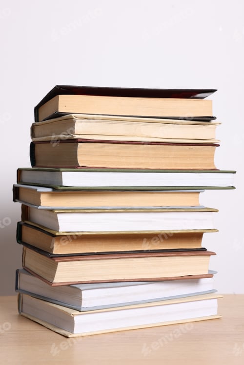 Preview: Stack of many books on wooden table against light background