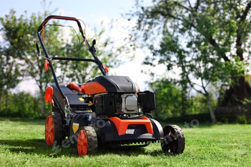 Preview: Modern lawn mower on green grass in garden