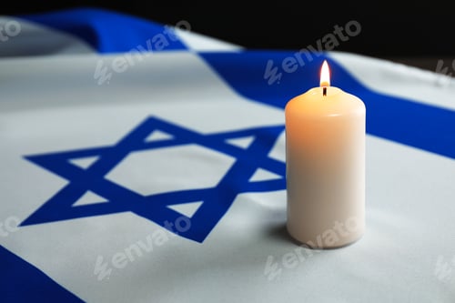 Preview: Holocaust Remembrance Day. Burning candle on flag of Israel, closeup