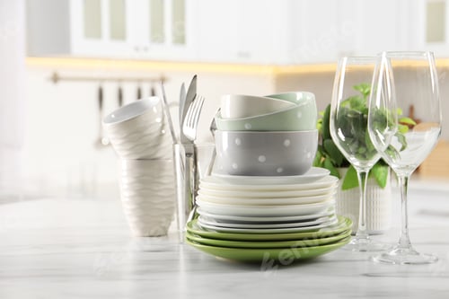 Preview: Many different clean dishware, glasses, cups and cutlery on white marble table indoors. Space for te